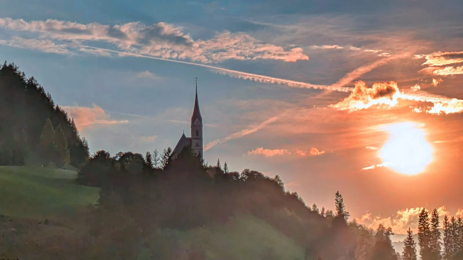 Church silhouette and village landscape at sunset
