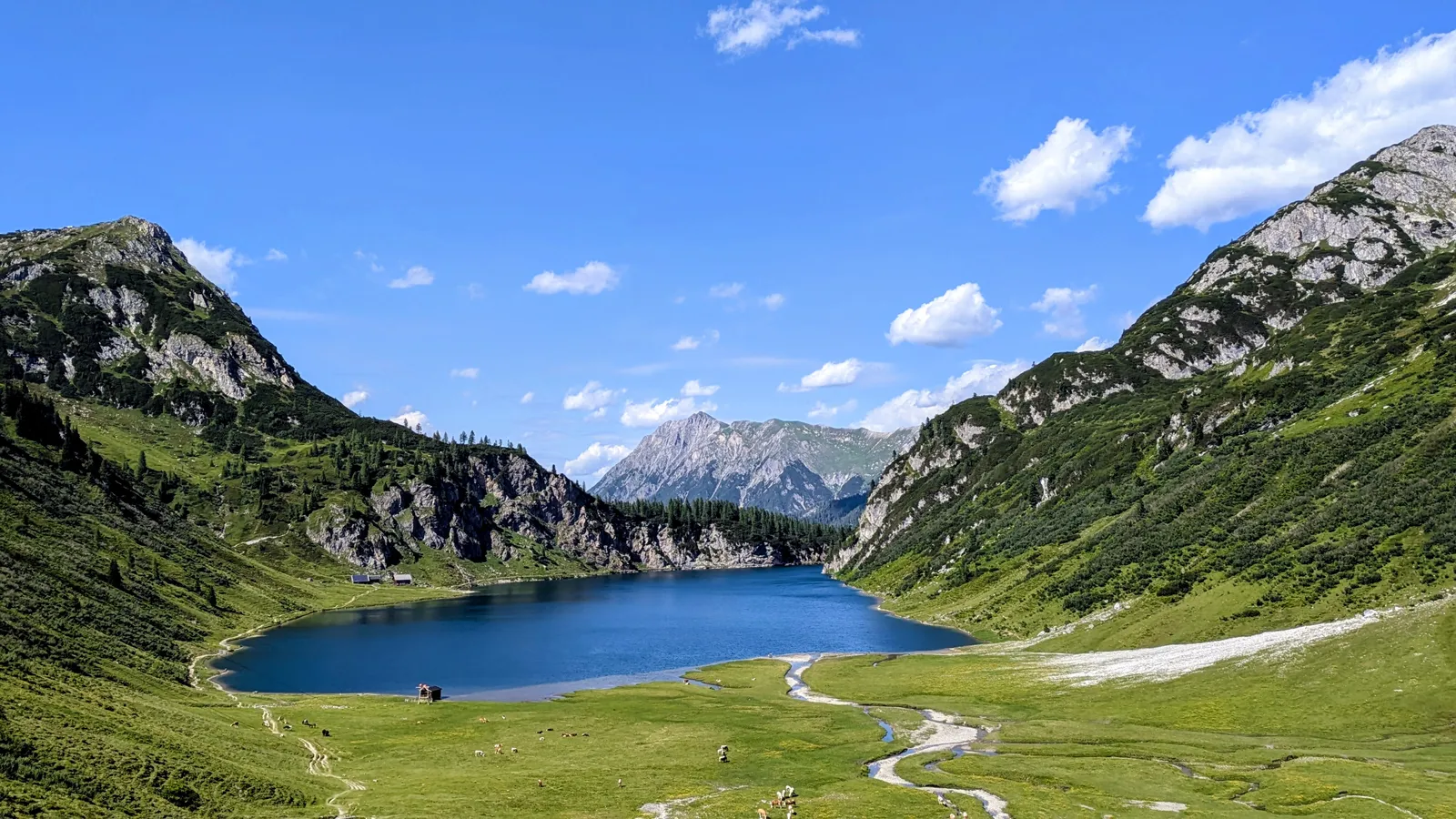 Blue mountain lake surrounded by steep green slopes