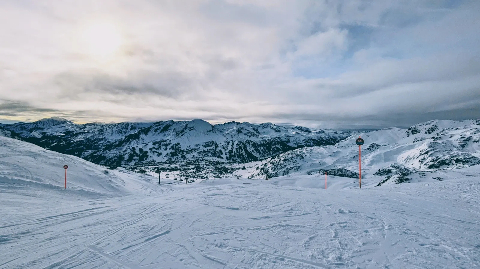 Panoramic ski slope with snowy mountains and piste markers