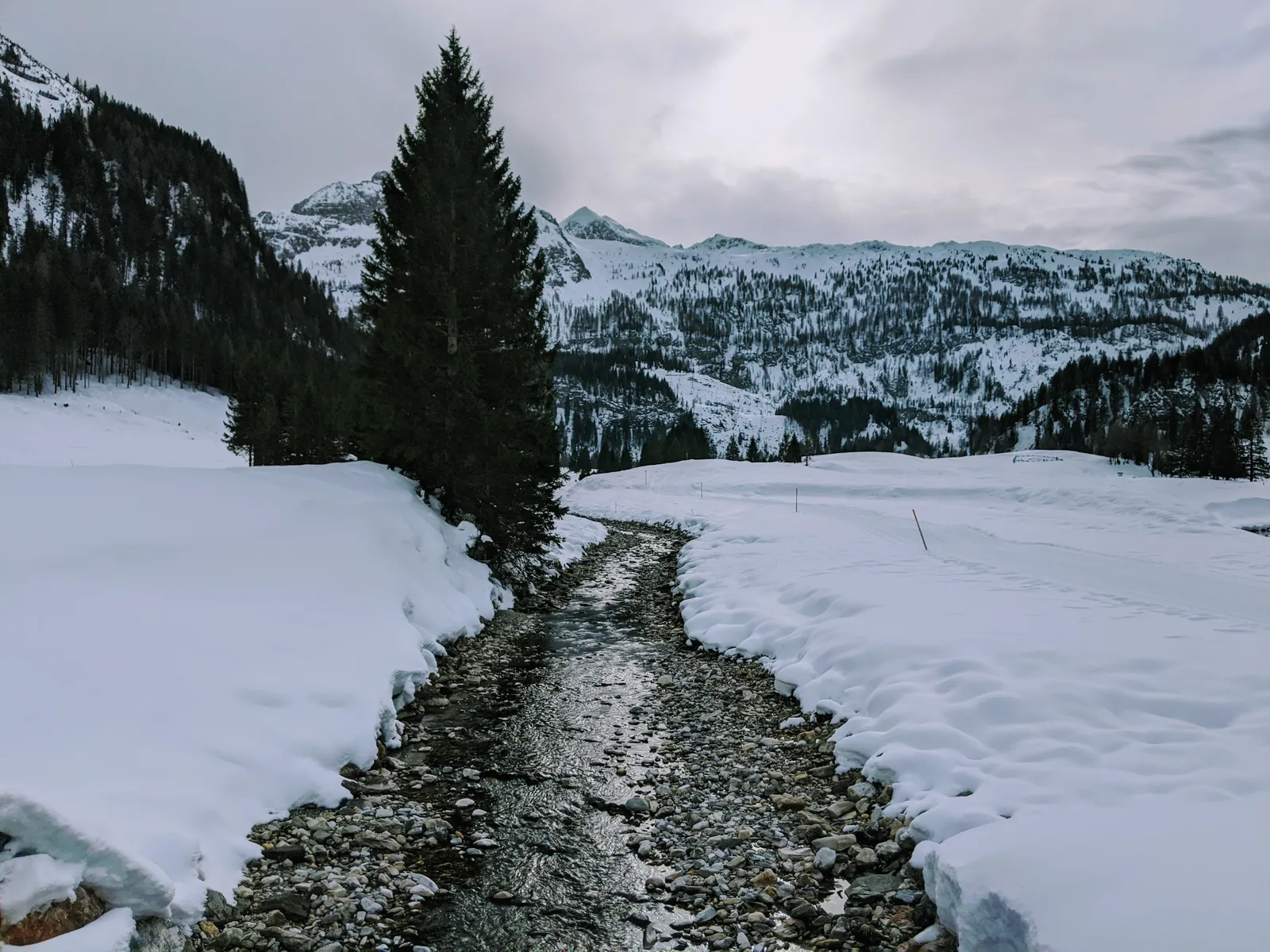Mountain stream flowing through snow in a winter valley