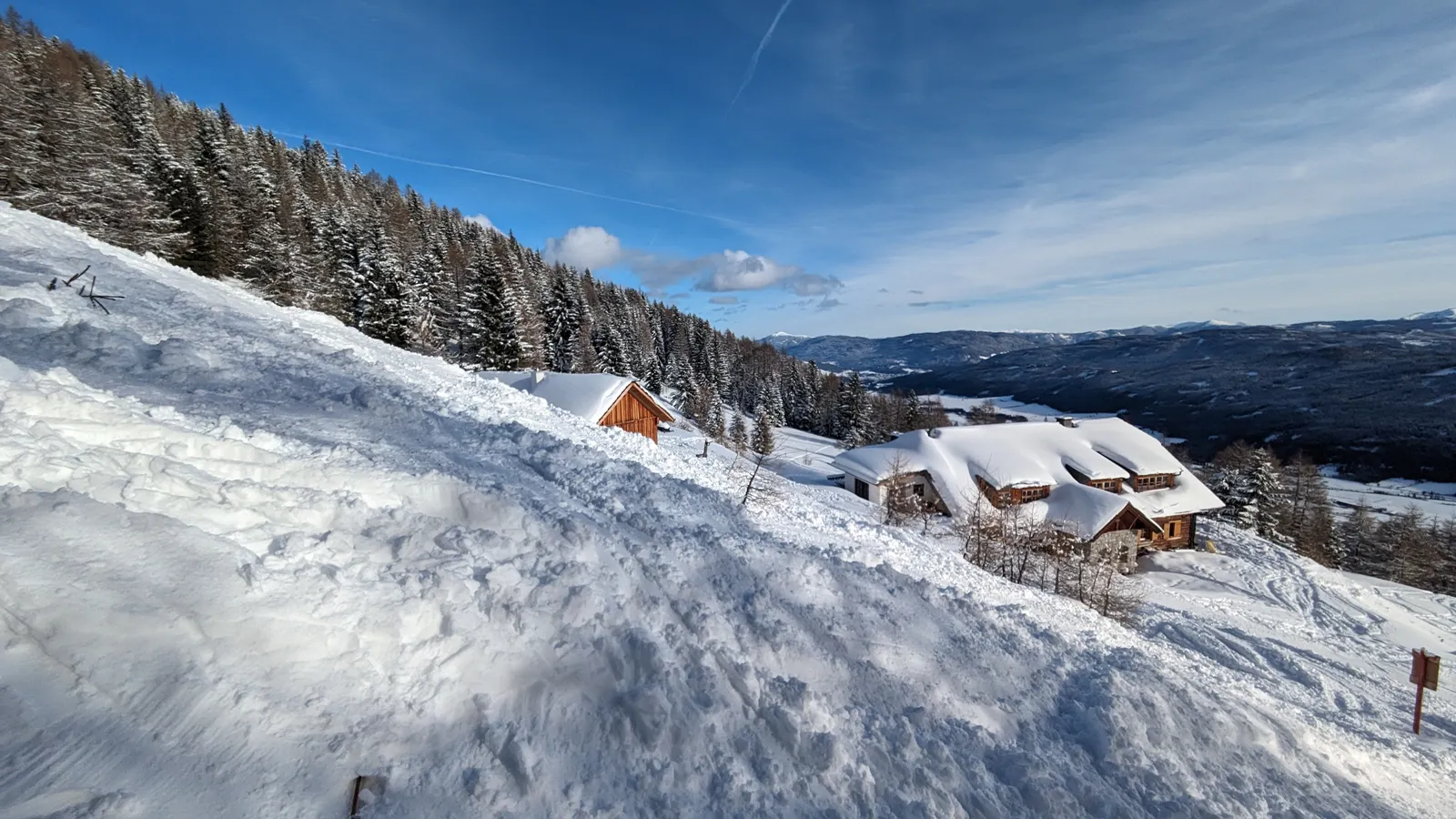 Snow-covered huts surrounded by forest and winter light